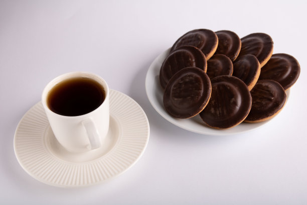 照片上有一杯咖啡，旁边放着满满一盘巧克力饼干图片下载