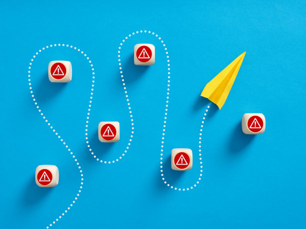 纸飞机穿过有危险警告标志的木块。图片下载