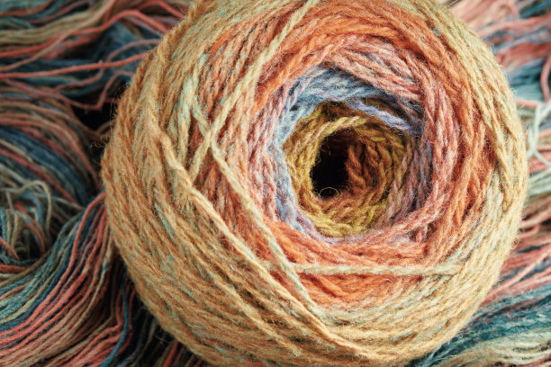 由纯有机羊毛制成的纱线球，绕在一束羊毛线上。彩虹的颜色。图片下载