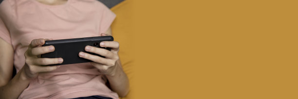 一个十几岁的女孩在家里客厅里用智能手机的特写图片，社交网络的概念，一组发给朋友和同学的短信。横幅图片下载