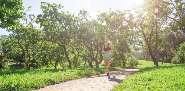 中年苗条的白人女子运动服跑步，在阳光明媚的夏天在公园慢跑训练。休闲活动，健康生活方式。横幅复制空间图片下载