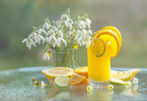 橙汁在杯子里，柑橘果和雪花莲花在早晨的阳光下。早餐在大自然，美丽的春天就在图片下载
