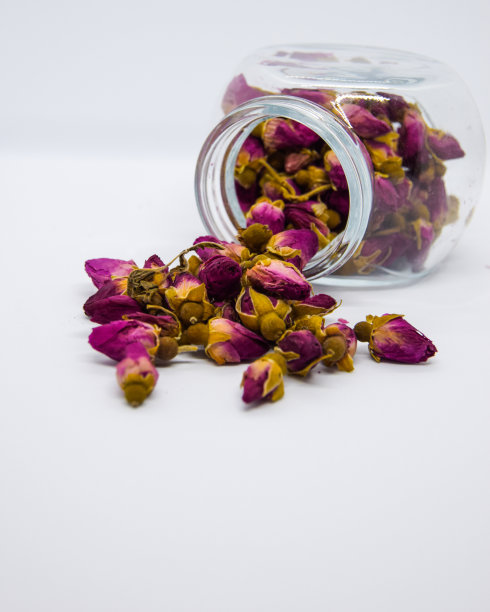 干燥的茶玫瑰花蕾孤立在白色上。近距离观察干燥的玫瑰花蕾在玻璃罐隔离在白色。图片下载