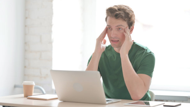 年轻人在笔记本电脑上工作时头痛图片下载