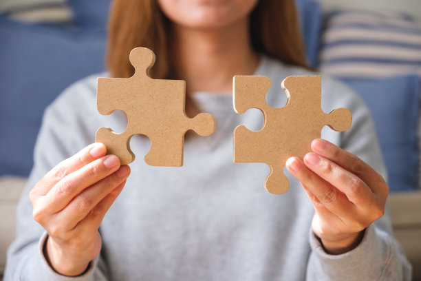 一个女人拿着一块木制拼图拼在一起的特写图像图片下载