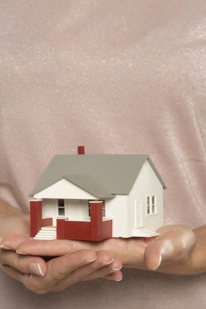 女人拿着房子样本模型孤立在米色背景，房地产和家庭保险的概念图片下载