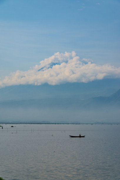 湖中央的渔船，背景是山景图片下载