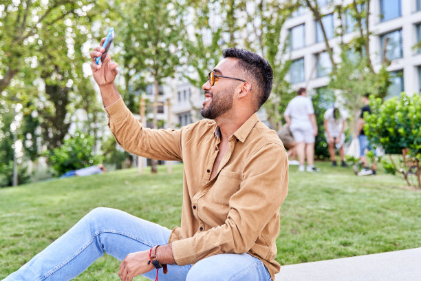 戴着墨镜和胡子的年轻人在户外用手机自拍图片下载