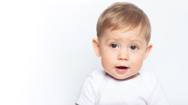 白人男婴在白色背景上啃木头牙齿。图片下载