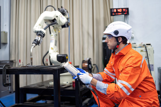 工程师手持控制器操作机械臂，在维修车间编程后进行运动测试图片下载