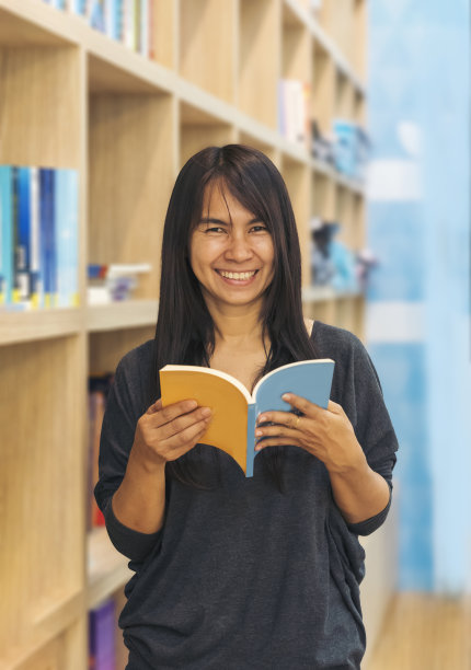 亚洲妇女在大学图书馆的书架上看书。年轻女子放松阅读开卷自学。大学女生在图书馆书店自学。教育学习知识图片下载