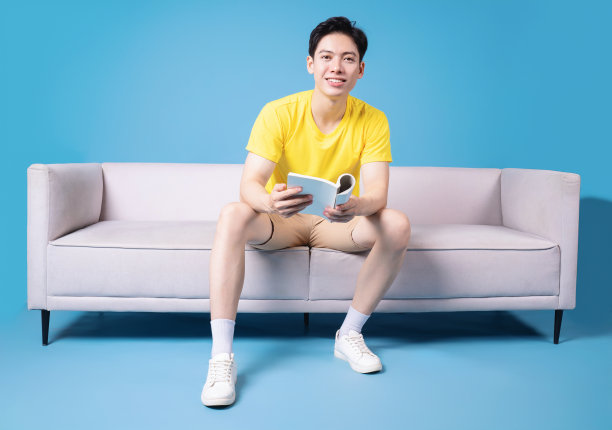 年轻的亚洲男子坐在沙发上的画面图片下载