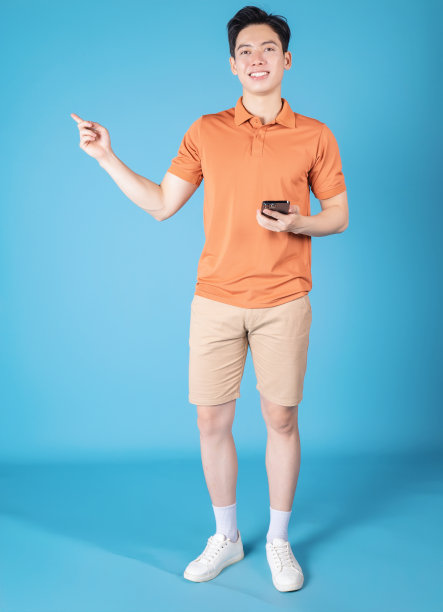 年轻的亚洲男子拿着智能手机的蓝色背景的图像图片下载