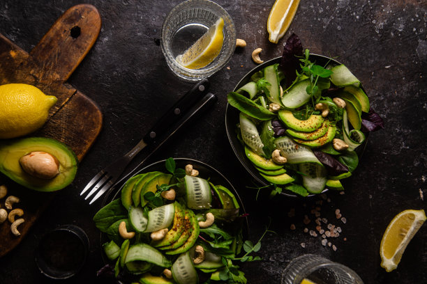 绿色蔬菜、黄瓜和牛油果沙拉放在黑暗的桌子上。素食菜图片下载