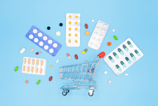 医学概念。各种胶囊、片剂和药品围绕在蓝色背景的购物车上。药的概念。购买药品。俯视图照片。图片下载