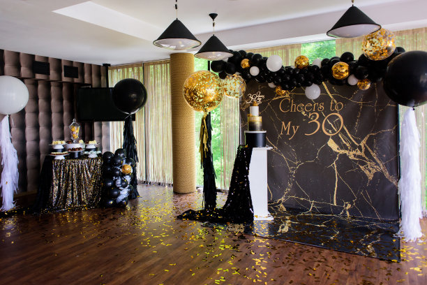 拍照区装饰有双层蛋糕、横幅、黑色和黄色气球。图片下载