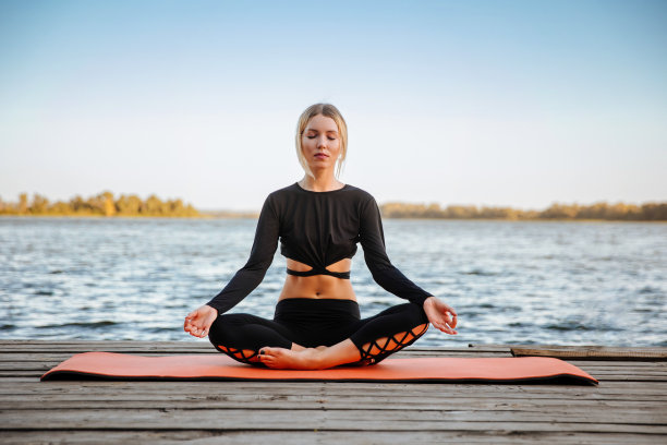 年轻女子练习瑜伽，呼吸，冥想在瑜伽垫上的莲花姿势图片下载