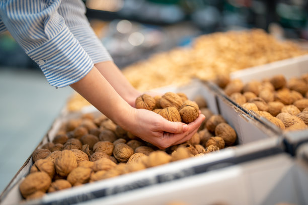 侧面的女性手拿起核桃在超市图片下载