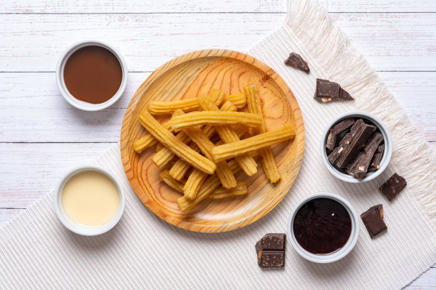 木盘与油条在桌子上，顶部视图与油条服务，放置在白色木桌附近的各种浇头在白色陶瓷碗，复制空间。图片下载