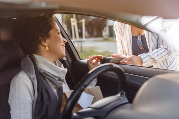 服务人员手持支付终端，年轻女子在路边取货处用信用卡付款图片下载