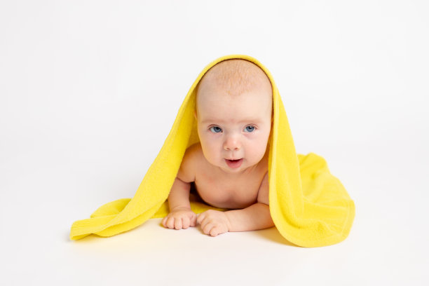 女婴沐浴后裹着毛巾在白色孤立的背景下看着镜头，婴儿3-6个月，空白文字图片下载