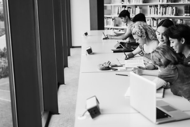 在大学图书馆学习的年轻多民族学生-关注金发女孩的脸-黑白编辑图片下载
