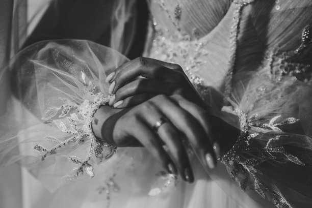 新娘把结婚礼服上的袖子拉直。风格复古优雅的连衣裙与蕾丝。婚礼上午的准备工作。黑白照片。图片下载