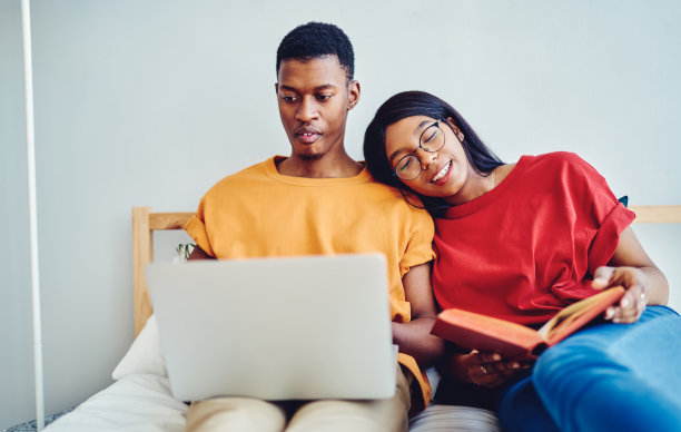 年轻的婚姻享受周末在家公寓一起娱乐，非裔美国男子选择电影在线观看休闲连接4g，而妻子躺在丈夫的肩膀上图片下载