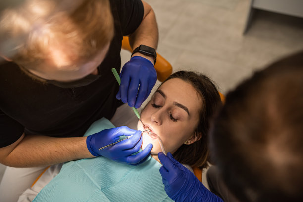 特写照片的妇女张开嘴与镜子的牙科设备。图片下载