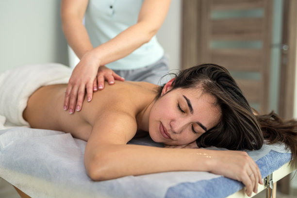女顾客躺在水疗沙龙的桌子上进行背部按摩图片下载