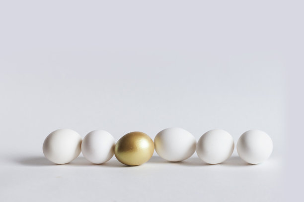 一个金蛋和五个白蛋排列在白色背景上，有复制空间图片下载