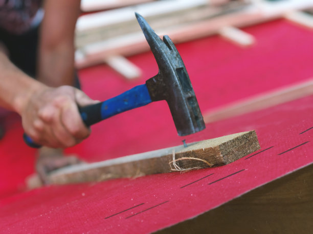 屋顶工人手里拿着锤子，在屋顶上的椽板上钉钉子，为未来的木制格子特写图片下载