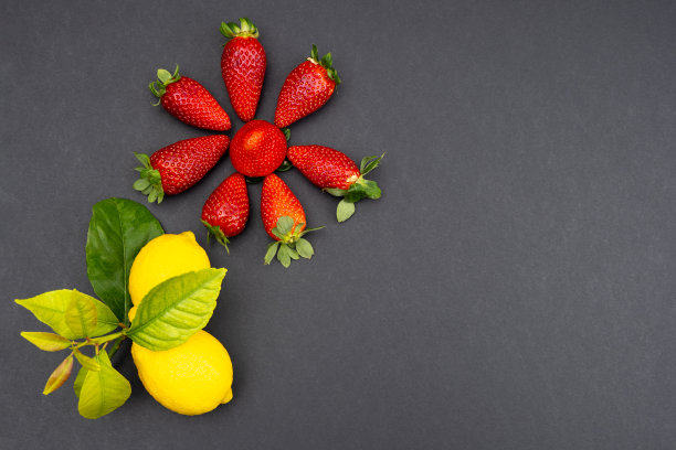 成熟的草莓和柠檬放在树枝上，背景是黑色的图片下载