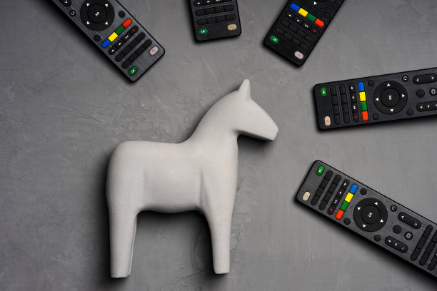 灰色背景的灰色玩具马，电视遥控器围绕着它图片下载