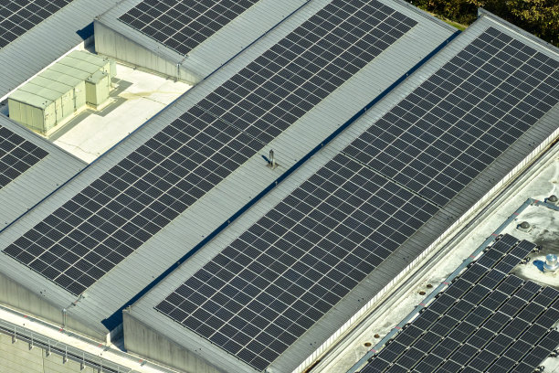 太阳能发电厂鸟瞰图，蓝色光伏板安装在工业建筑屋顶，生产绿色生态电力。生产可持续能源的概念图片下载