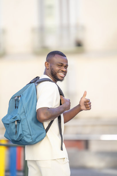 侧面视图肖像的一个人与黑色皮肤与背包在街上给了ok图片下载