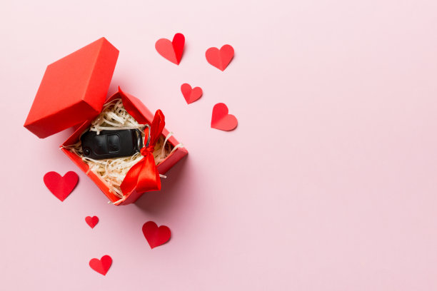 黑色的车钥匙装在礼品盒里，礼品盒上有彩带和红心。情人节作文顶视图图片下载