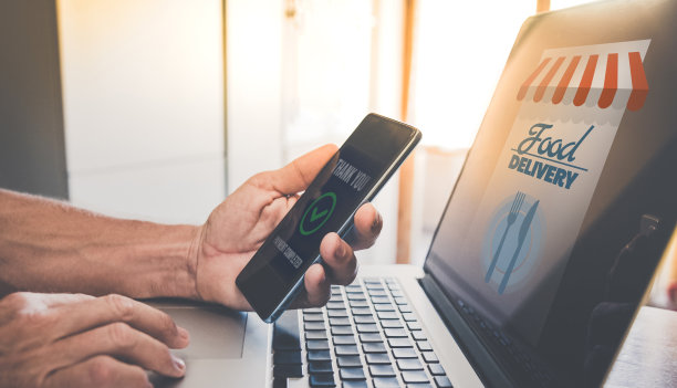 男子用电脑在网上购买食物并付款。手持智能手机。送货上门，餐饮理念图片下载