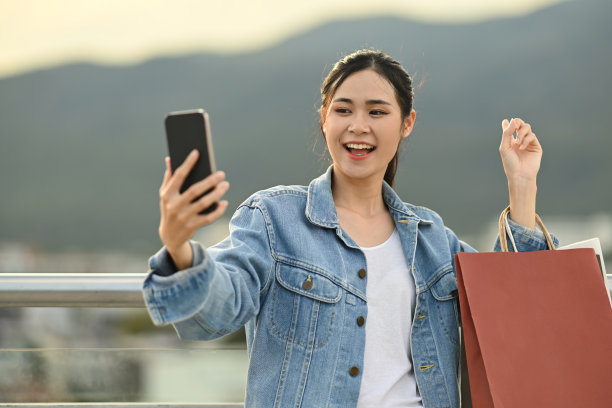 开朗的亚洲妇女正在用手机打视频电话，站在露台上，背景是夜空。图片下载