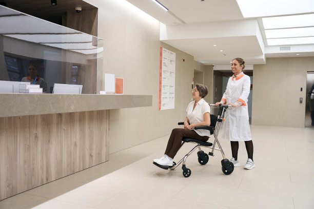 医护人员正把坐轮椅的老年病人带到接待处图片下载