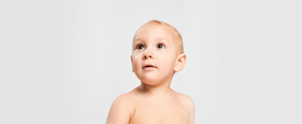 特写小可爱的学步男孩，婴儿好奇地看着孤立的灰色工作室背景。童年、母亲、生命、出生、家庭、幸福的概念。图片下载