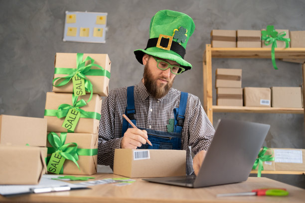 创业中小企业中小企业主男性企业家在收货箱上写地址并检查网上订单，装箱，在圣帕特里克节卖给客户，中小企业创业思路图片下载