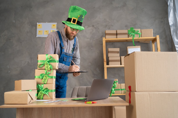 创业中小企业的男老板用笔记本电脑在网上接订单打包箱子，卖给客户，中小企业网上创业。圣帕特里克节大减价图片下载