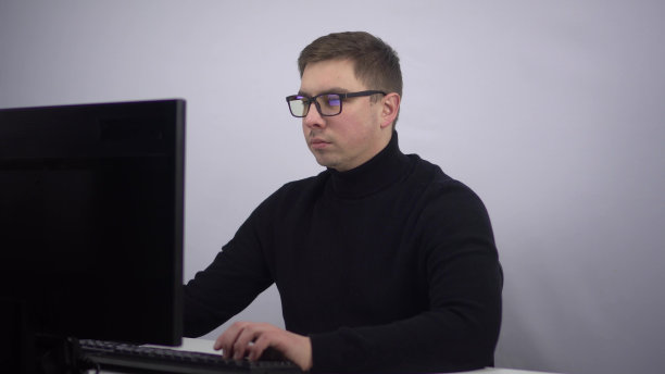 一位IT专家坐在办公室的电脑前，突然有了一个主意。这个年轻人在办公室工作。图片下载