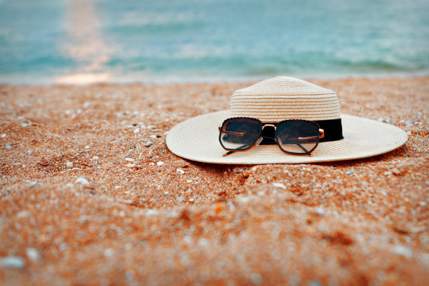 沙滩上放着一顶带黑色墨镜的草帽。在酒店的家庭度假。在海滩上放松一下。旅行社广告。图片下载