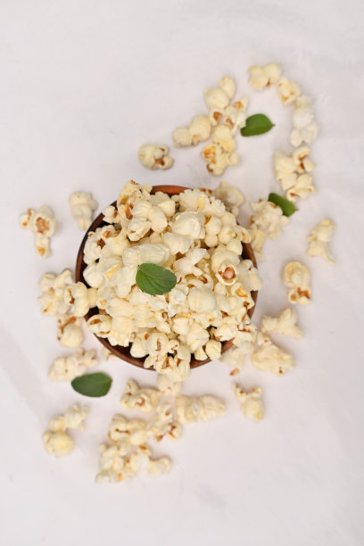 特写一束白色黄色的爆米花，绿色的薄荷叶孤立在白色背景上。图片下载