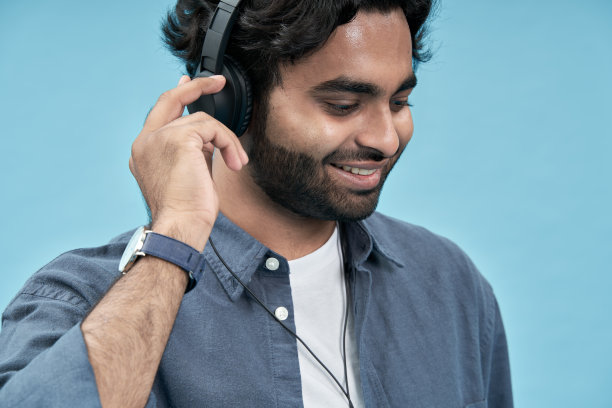 微笑的阿拉伯男学生戴着耳机听音乐特写图片下载