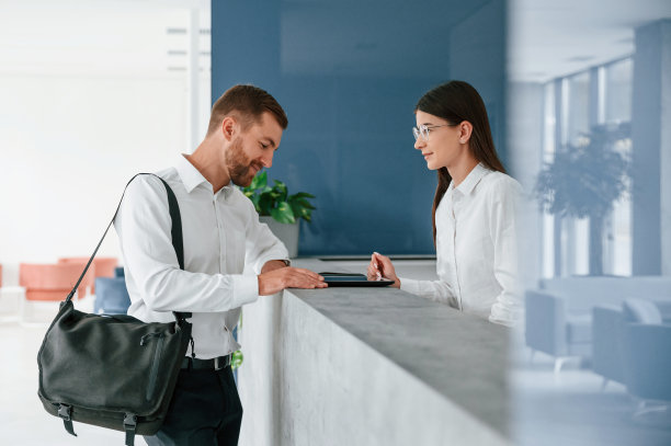 在接待。穿白衬衫的男子在一名女子的帮助下在旅馆订房间图片下载