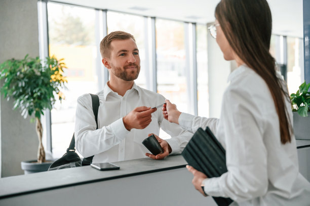 协助客户。穿白衬衫的男子在一名女子的帮助下在旅馆订房间图片下载