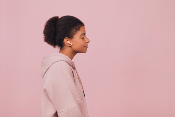 带着无线耳机的黑人年轻女子的特写肖像。图片下载